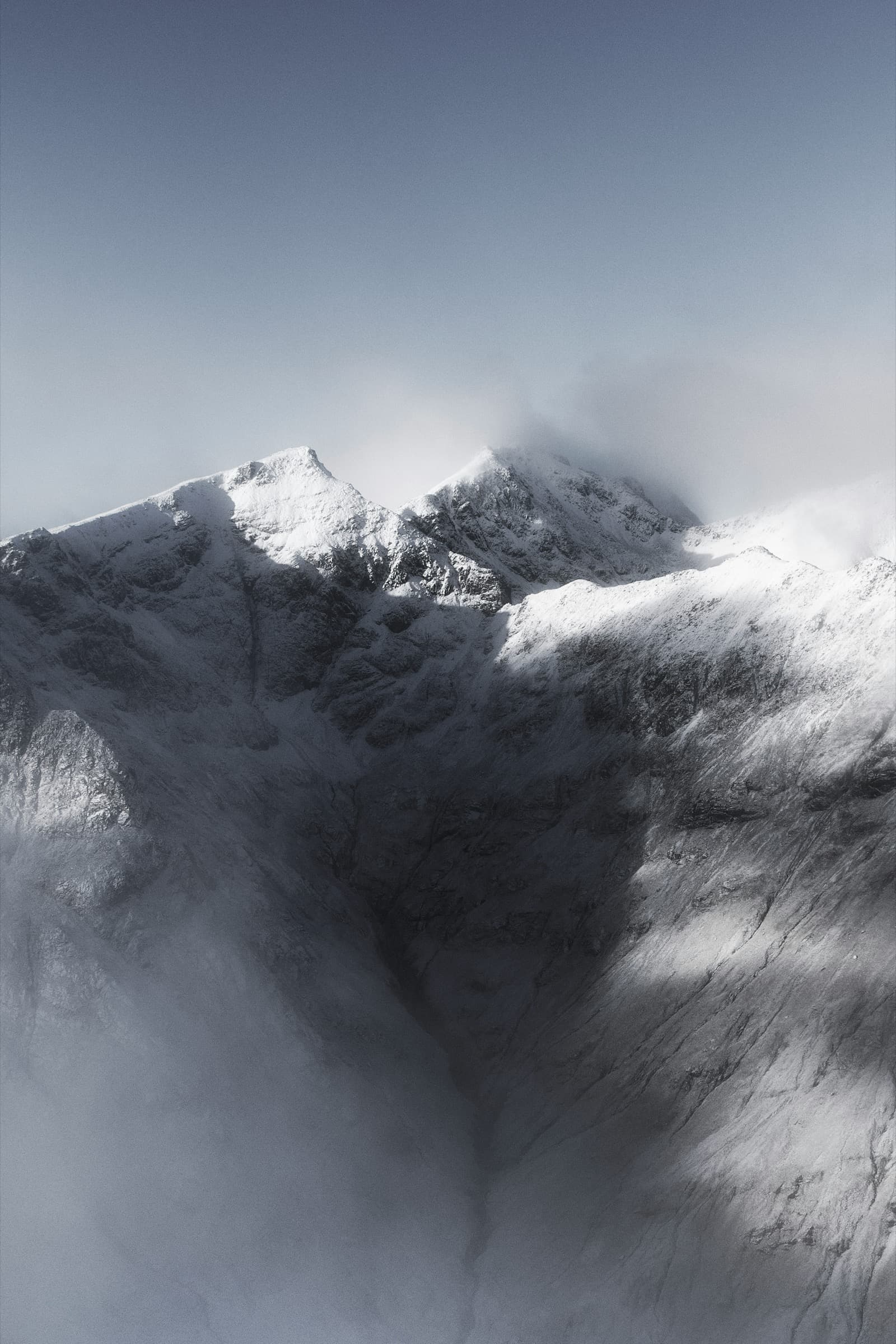 Snow-dusted ridgelines emerging from cold morning mist